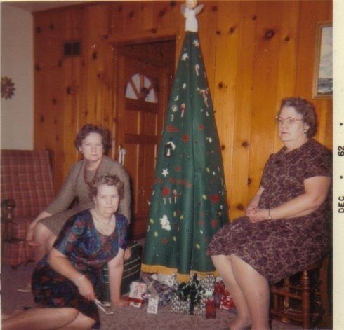Drie dames met een kerstparasol doen alsof kerst gezellig is.