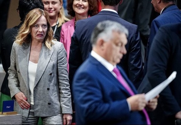 Georgia Meloni looking at Orban with a disgusted expression at the NATO summit.