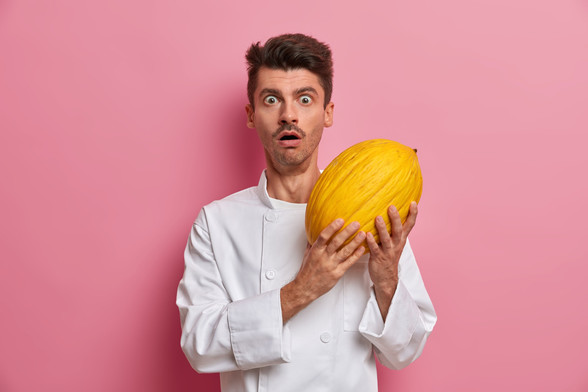 Cocinero sujetando un melón amarillo con cara de asombro