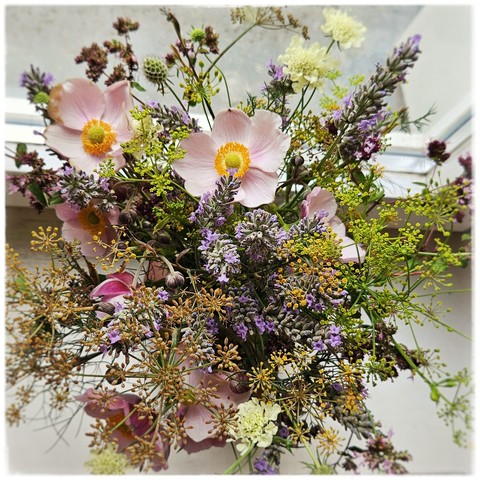 Blick von oben auf einen Blumenstrauß mit rosa Anemonen, lichtblauem Lavendel, braunrotem Oregano, Gelber Skabiose, und gelbem Fenchel und grüngelbem Pastinak