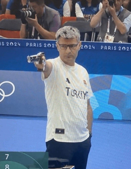 
Yusuf Dikec (Turquía) disparando. Tiene una aptitud tranquila con la mano izquierda en el bolsillo y la derecha con una pistola. Está participando en los juegos olimpicos de paris 2024 y así se puede ver en un letrero al fondo.