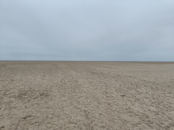 Zweigeteiltes Bild: oben grauer Himmel, unten Sand 