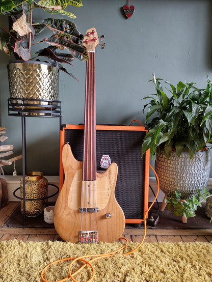 A four string fretless bass leaning against an amplifier. 