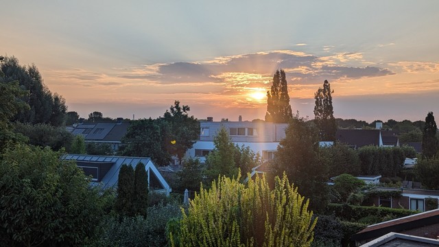 foto opkomende zon met stralen langs wat kleine wolken.