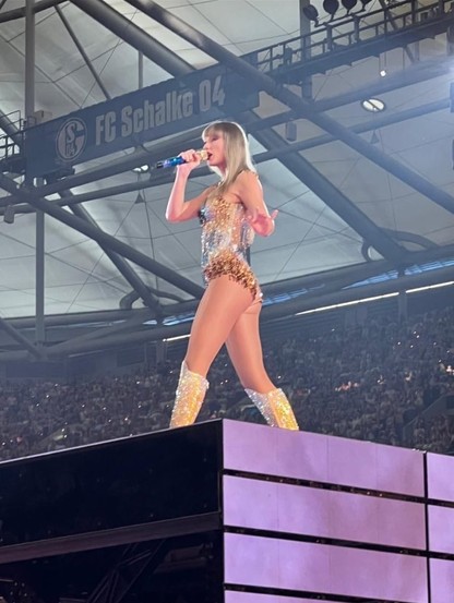 Photo of Taylor Swift in concert in Schalke's stadium. Swift in the foreground, in the back a stadium sign with 