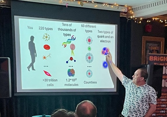 Tim Coulson stands in front a slide showing the composition of the human body through different lenses:

- 220 types of cell
- 10s of 1000s of proteins
- 60 types of atom
- but two types of quark and an electron