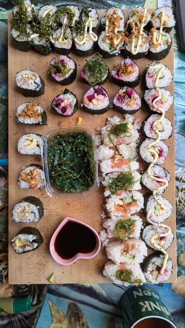 foto plank met veel sushi stukjes er op.