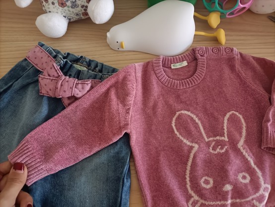 Un jersey rosa con un conejito impreso junto a unos vaqueros pequeñitos de talla 3 meses