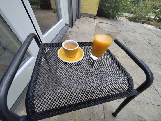 bijzet tuin tafeltje met daarop een kopje espresso en een glas duindoorschorle