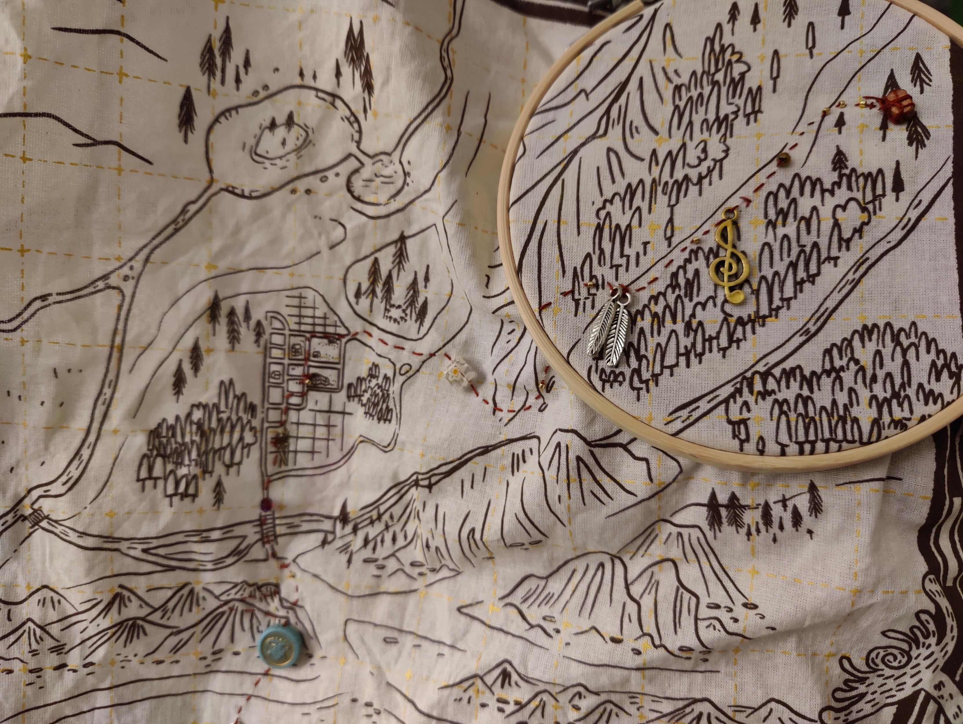 Bordado rojo con cuentas de diferentes formas sobre una tela con un mapa impreso