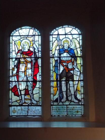 A two-paned stained glass window. Two medieval soldiers, left mostly red, right mostly blue.
