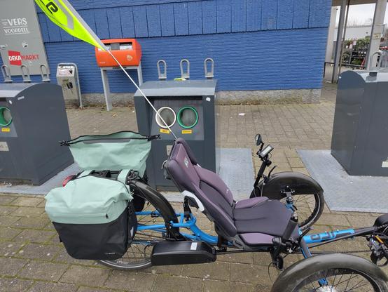 trike met fietstassen bij de glasbak
