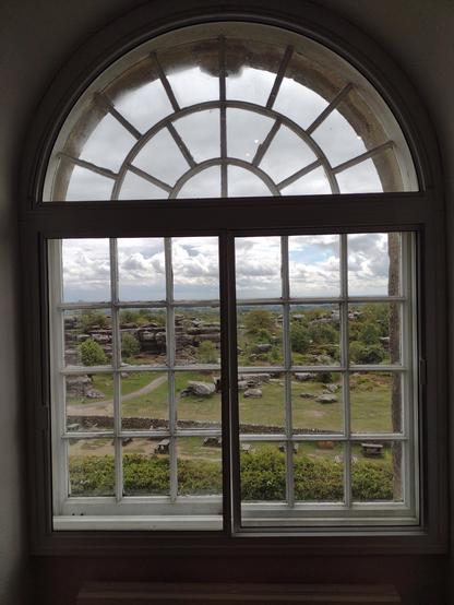A sandstone rock outcrop seen through a Georgian round top window