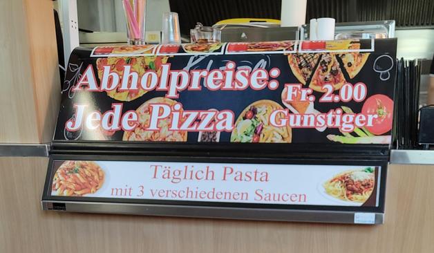 Eine Werbung am Tresen mit der Aufschrift: Abholpreise: Jede Pizza Fr. 2.00 Gunstiger.