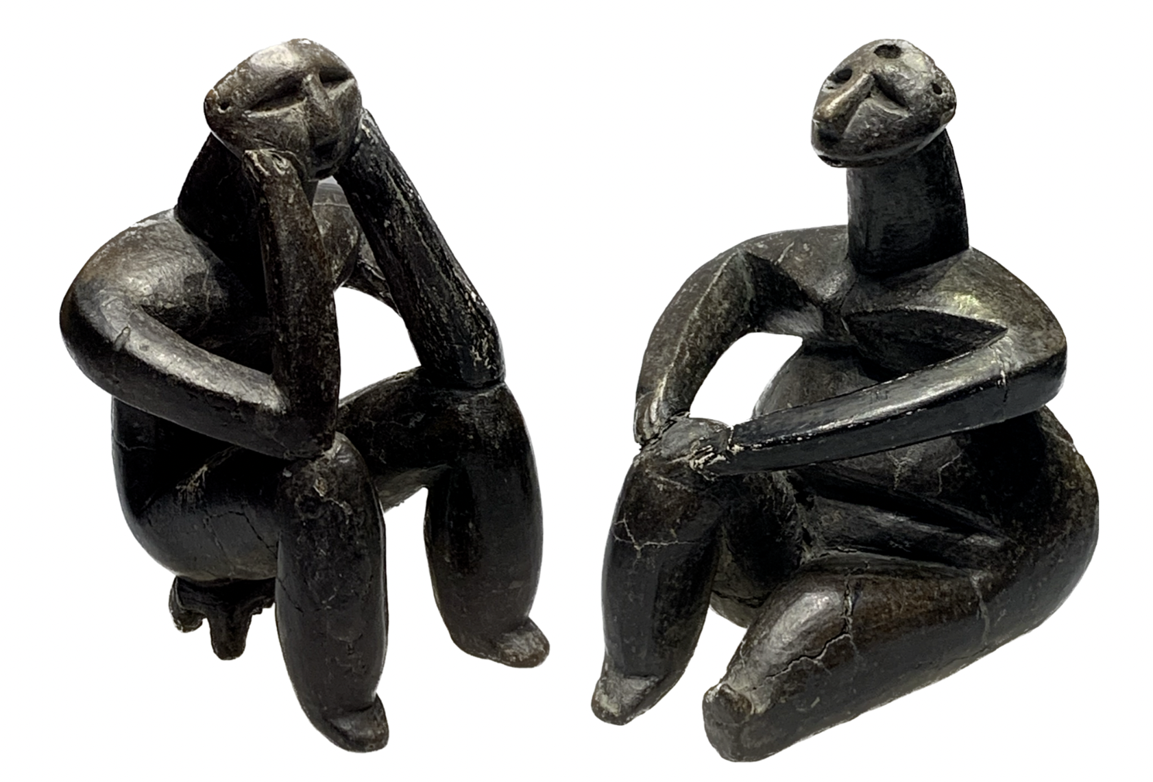 two small dark terracotta figurines - a seated figure with elbows on knees & chin resting in hands, not dissimilar to Rodin's Thinker, beside a seated figure with one knee bent. Hamangia neolithic sculptures - Romania, c. 5000 BC.