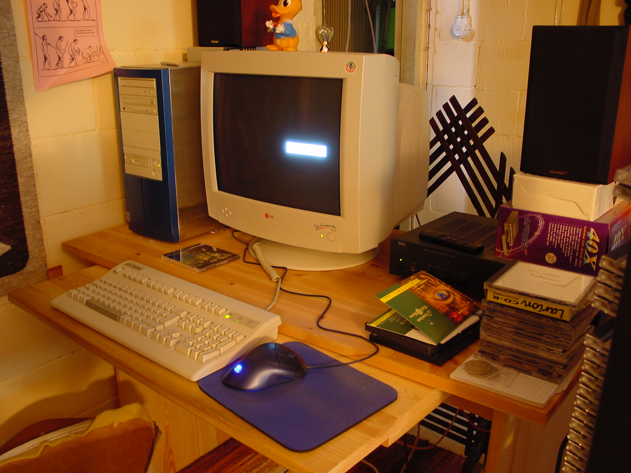 Old tower computer and 19" CRT monitor on a desk with a integrated amp and some speakers by its side