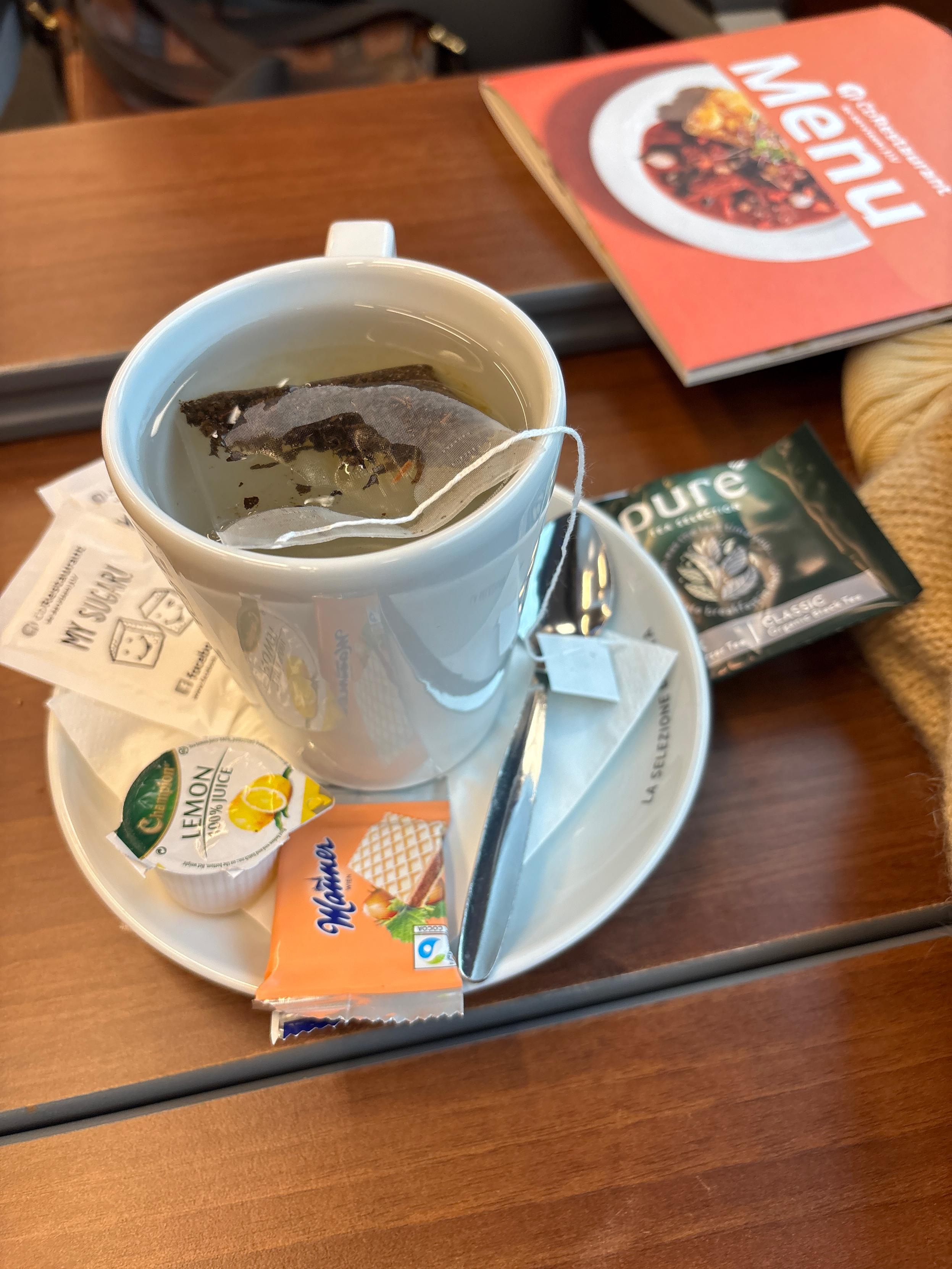 A cup of tea, in a proper cup, with a little cookie on the side. 