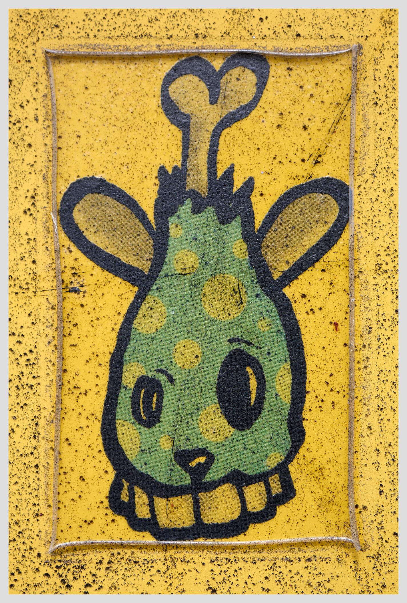 Vertical closeup of a transparent sticker on a yellow electrical box.